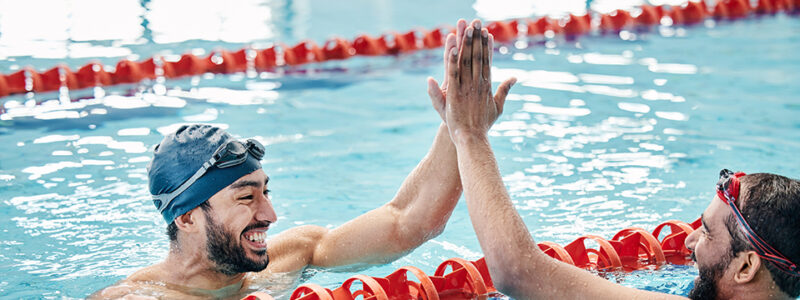 People high five in swimming pool.